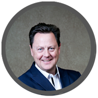 Mark Williams from the Pikes Peak Pros Business Networking Group in Colorado Springs, wearing a suit, is smiling in a circle.