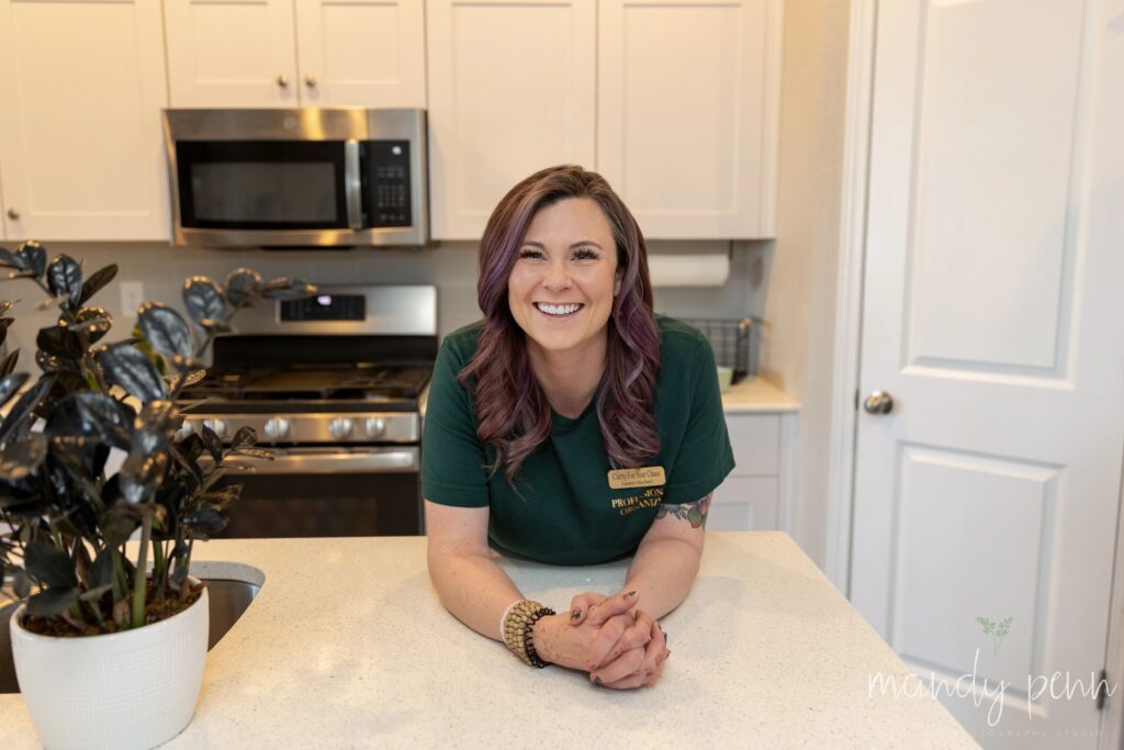 A woman in a green shirt sitting in a kitchen.