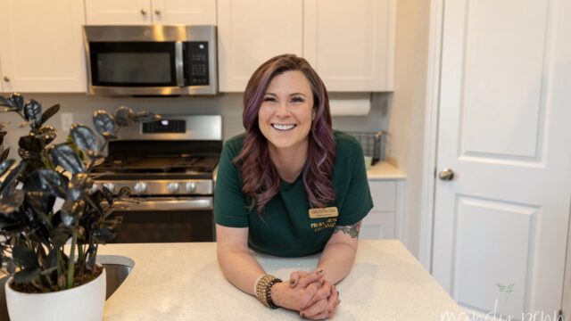 A woman in a green shirt sitting in a kitchen.