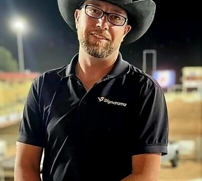 A man in a cowboy hat standing in a rodeo arena