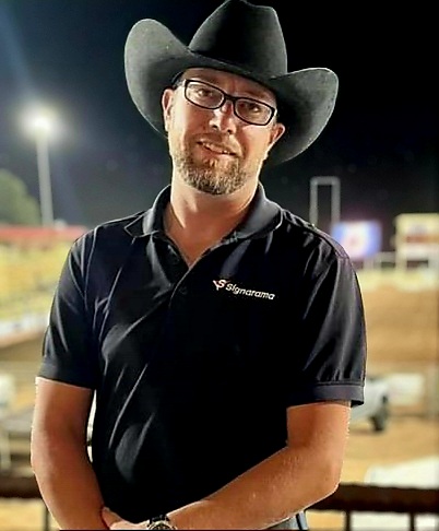 A man in a cowboy hat standing in a rodeo arena