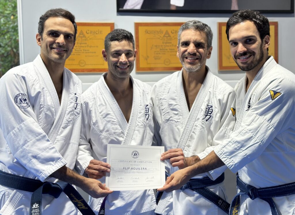 Four men in white judo uniforms smiling and holding a certificate.